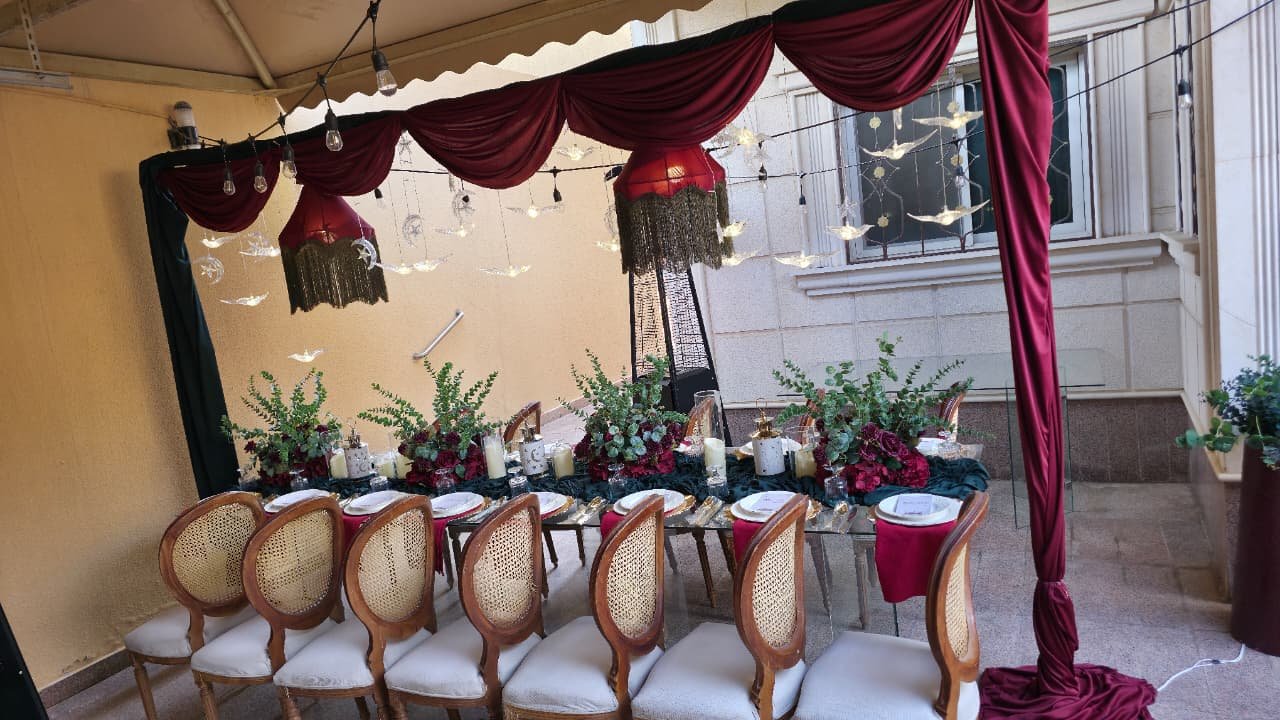 طاولة زجاجية خارجية بمفرش أخضر وورد أحمر